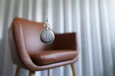 silver round pendant on brown wooden chair