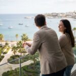 Jeune couple regardant l'océan depuis leur balcon moderne
